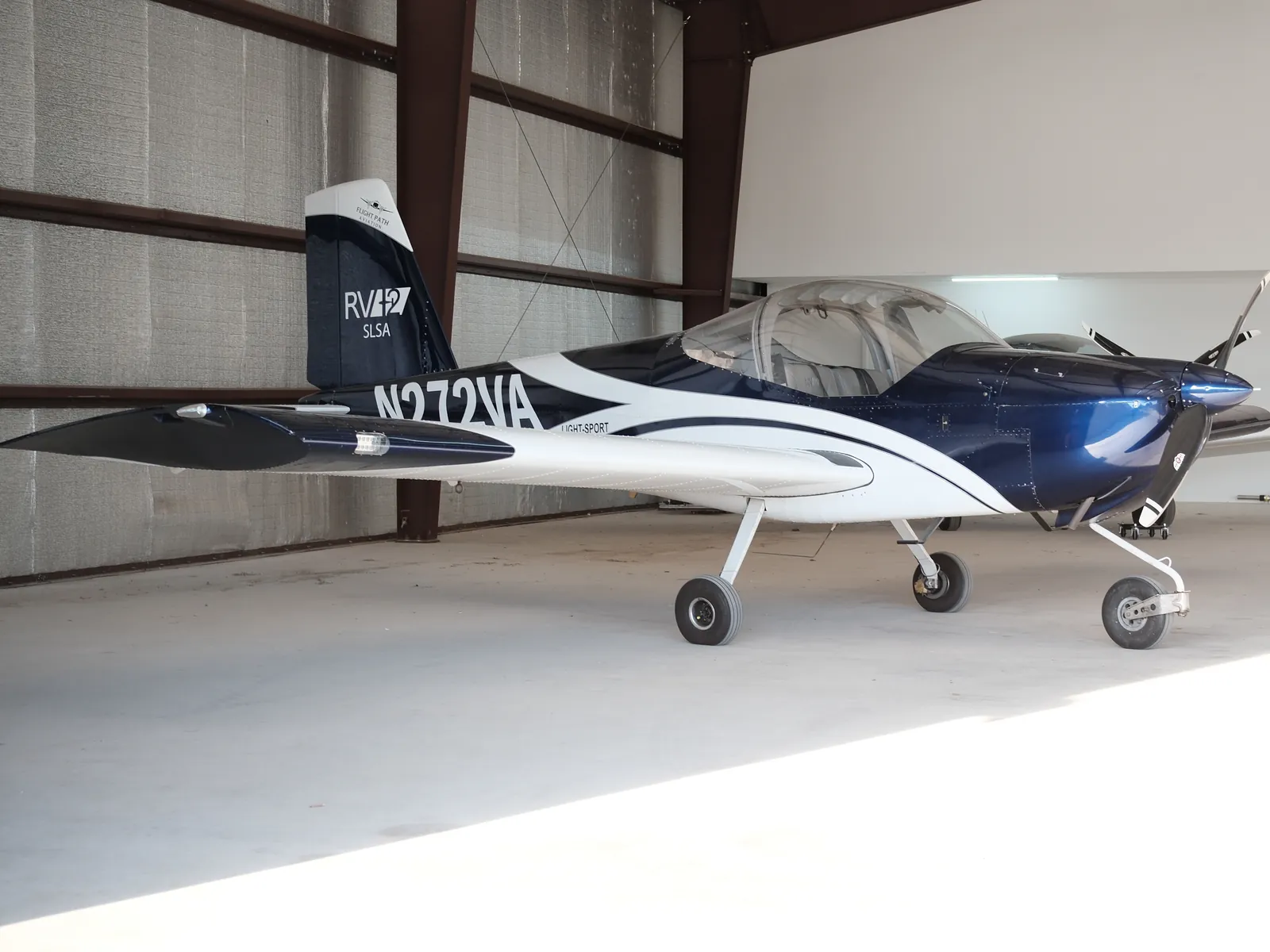 N272VA, a blue and white Van's RV-12 ULS, parked inside a hangar