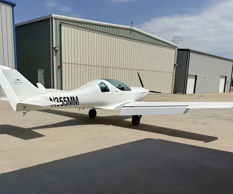 N355MM, a white Aerospool Dynamic WT-9, parked on the ramp in front of hangars