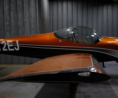 Side view of N812EJ, the orange RV-12iS, showing its tail number and bubble canopy