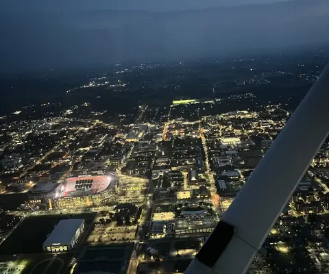 City lights at night seen from the cockpit over the wing strut